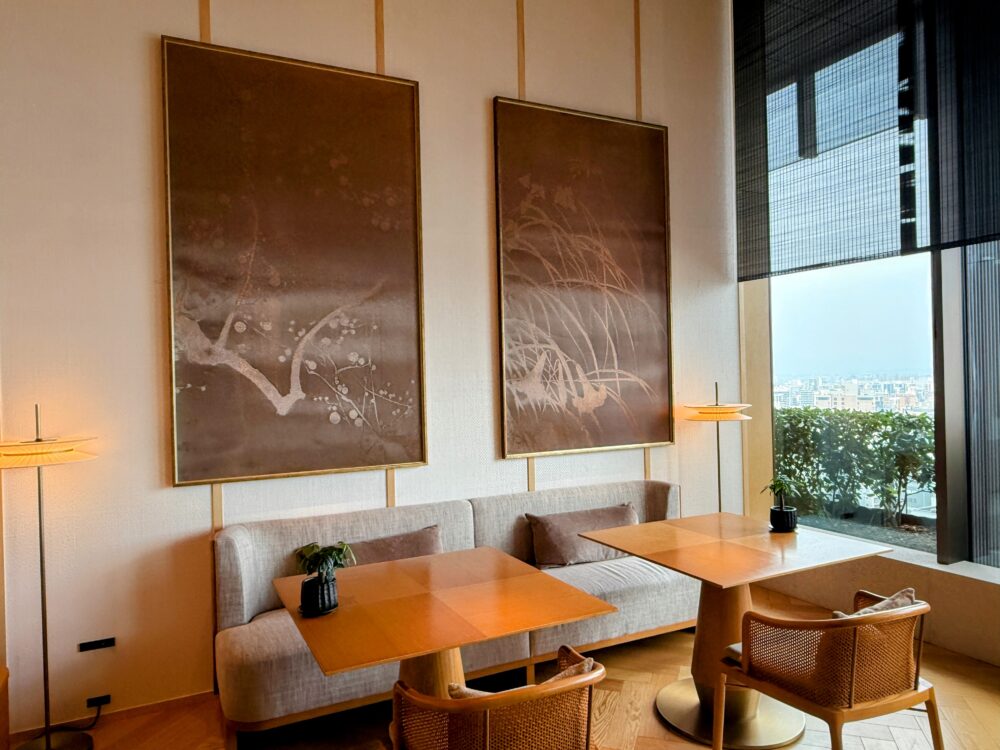 レストランの座席エリア。背面の壁には植物が描かれた大きなアート作品が飾られている。