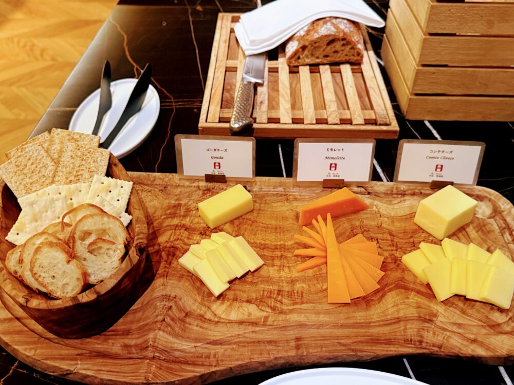 木製プレートに盛り付けられたチーズ3種（ゴーダ、ミモレット、コンテ）とバゲット