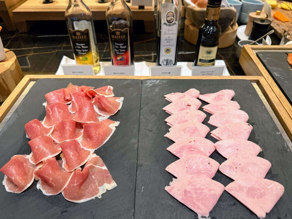 黒いスレートプレートに並べられた生ハムとボロニアソーセージ