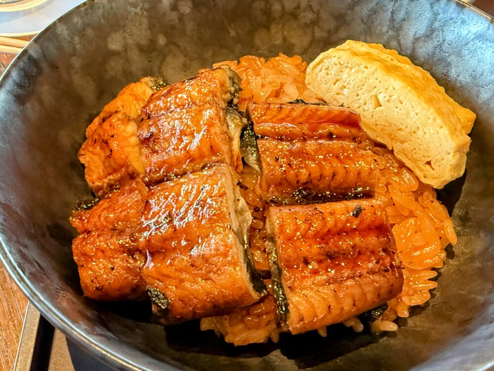 香ばしく焼き上げられた鰻と厚焼き玉子が乗った「うな重」のアップ