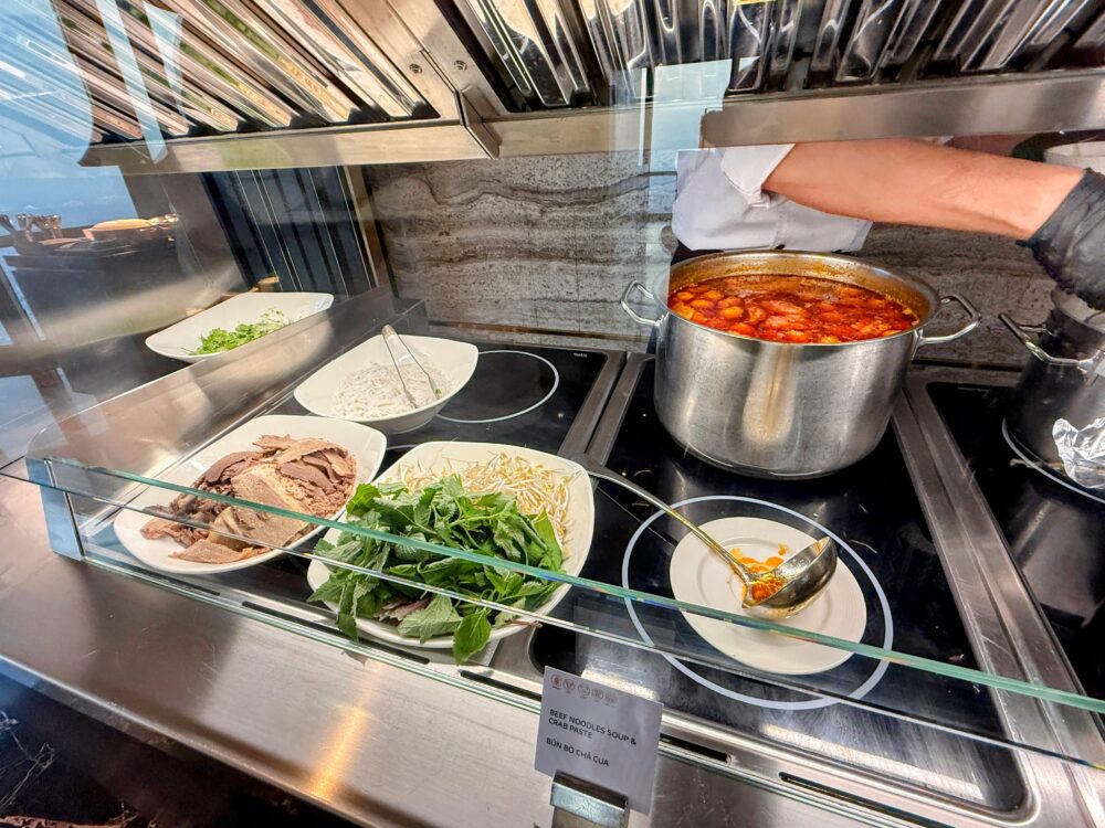 ライブヌードルステーションの大きな寸胴鍋。たっぷりの赤いスープと具材(牛肉やカニ団子)が入っており、食欲をそそる。