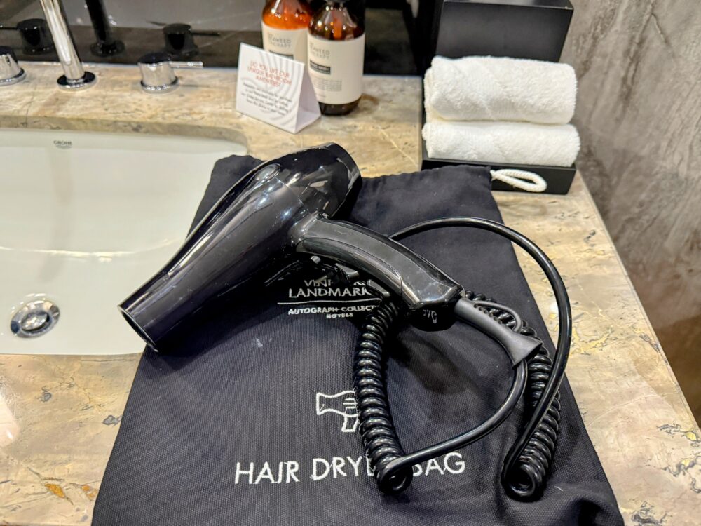 黒い巾着袋の上に置かれたヘアドライヤー。シンプルで使いやすそうなデザイン。
