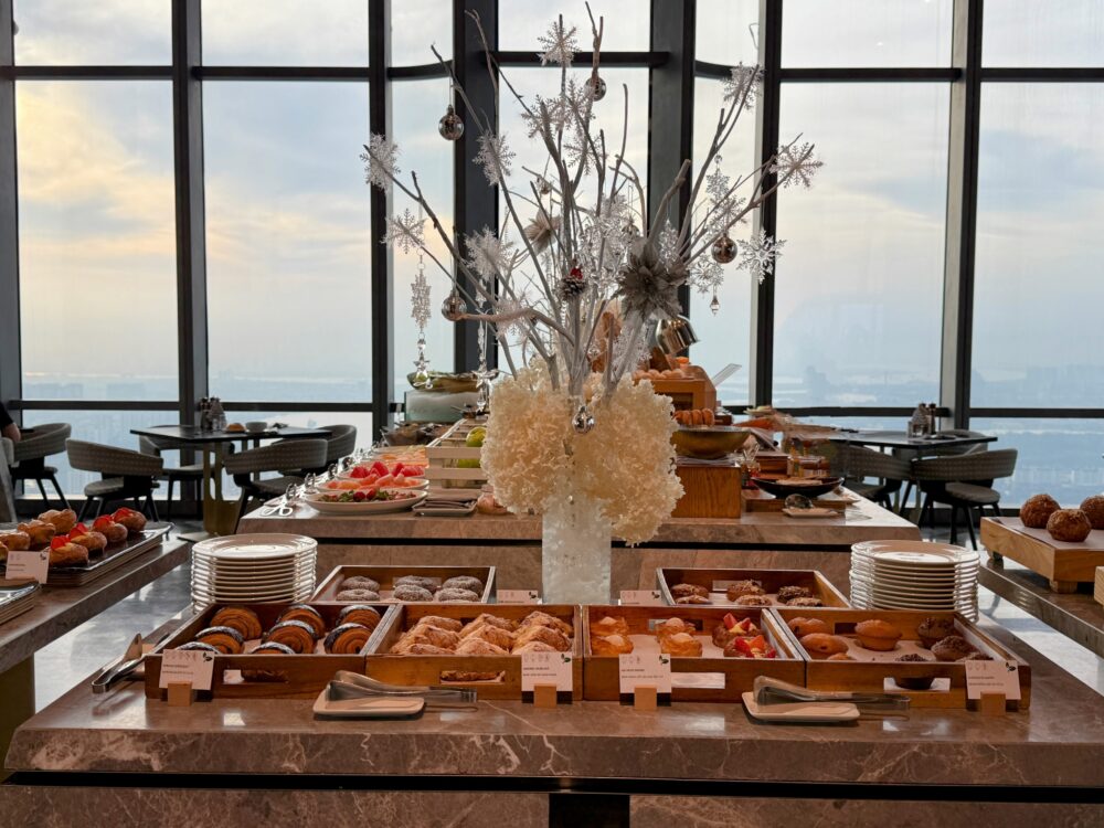 66階レストラン「Oriental Pearl」の朝食会場。大きな窓から朝日が差し込み、白いクリスマスツリーが飾られた明るく開放的な空間。
