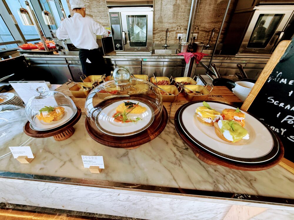 卵料理コーナーで調理をするシェフの後ろ姿。カウンターにはエッグベネディクトやスクランブルエッグの見本が置かれている。
