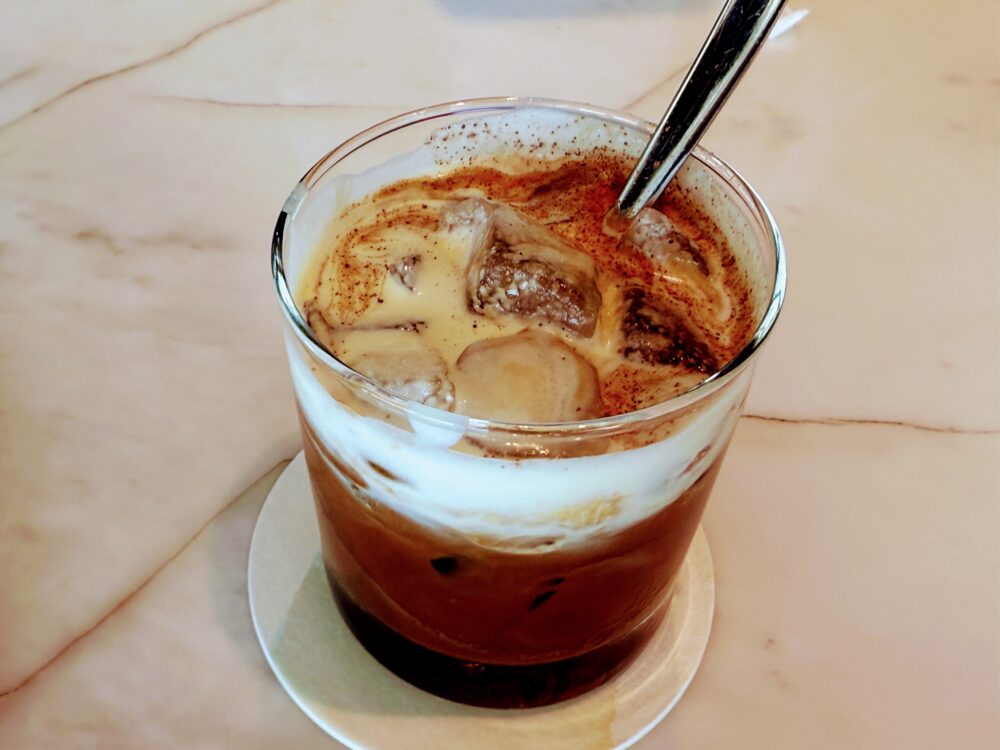 クラブラウンジで提供されるベトナム塩コーヒー。濃厚なコーヒーの上に厚い塩クリームの層があり、ココアパウダーがトッピングされている。
