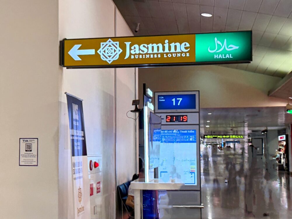 ホーチミン空港国際線ターミナル、17番ゲートの案内表示板の横にある「Jasmine BUSINESS LOUNGE HALAL」と書かれた左矢印付きの吊り下げ看板。