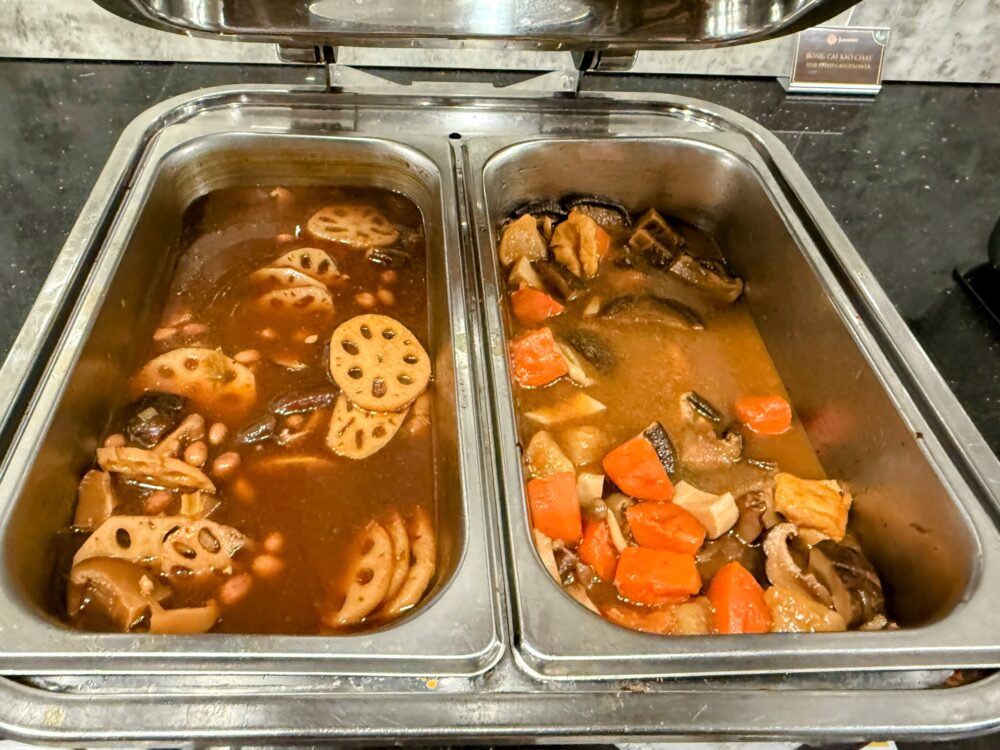 レンコン、豆、椎茸などが入った茶色い煮込み料理と、人参や野菜が入ったとろみのある煮込み料理が並んでいる。