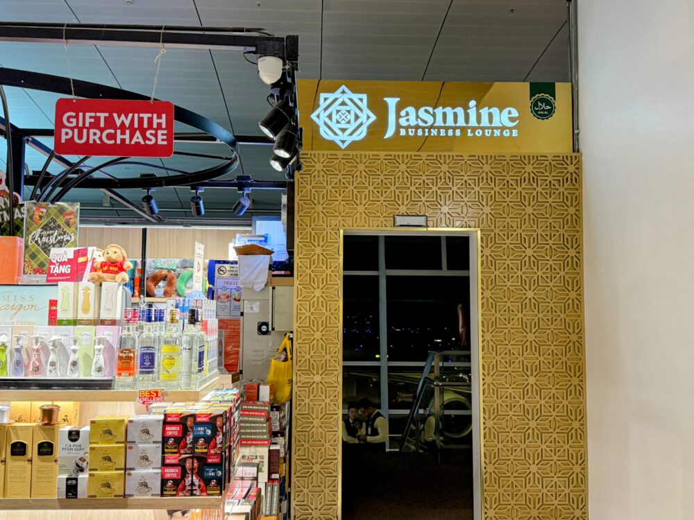 土産物店の奥に設置されたJasmine Halal Loungeの入り口。金色の幾何学模様が施された壁面と、上部で白く発光するラウンジ名のロゴサインが特徴的。