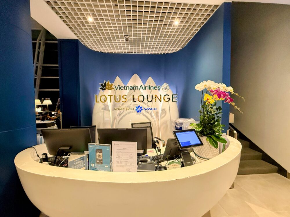 ベトナム航空ロータスラウンジ2の受付カウンター。青い壁にゴールドの文字でLOTUS LOUNGEと書かれている。