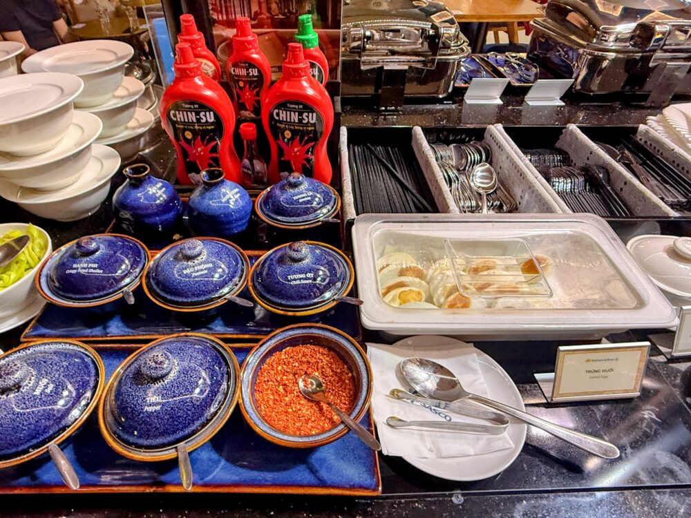 フォー用の調味料コーナー。チリソースのボトル、フライドエシャロット、唐辛子、各種タレが入った壺が並ぶ。