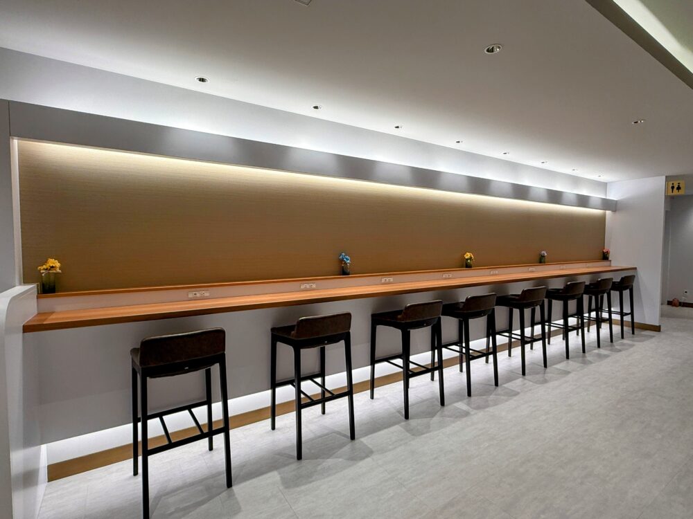 壁に向かって設置された木目のカウンター席。電源コンセントが完備されており、PC作業や一人での利用に適している。