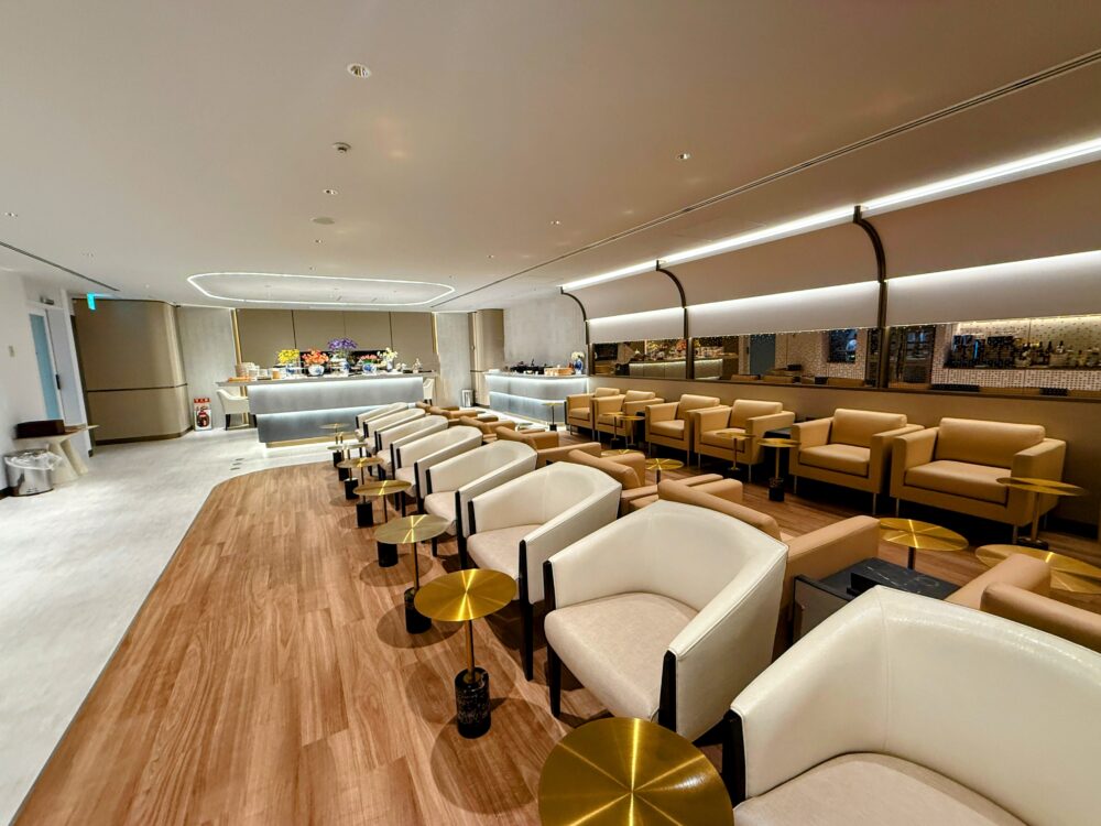 白を基調とした明るいダイニングエリア。奥にはビュッフェカウンターがあり、モダンな白いアームチェアとサイドテーブルが配置されている。