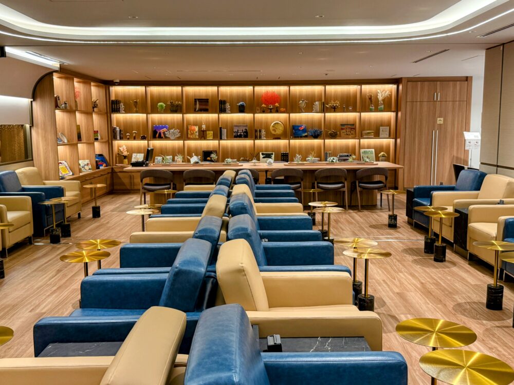 コーラルラウンジ鶯のメインフロア。壁一面の木製棚に洋書や小物が飾られ、ブルーとベージュのソファー席が並ぶ広々とした空間。