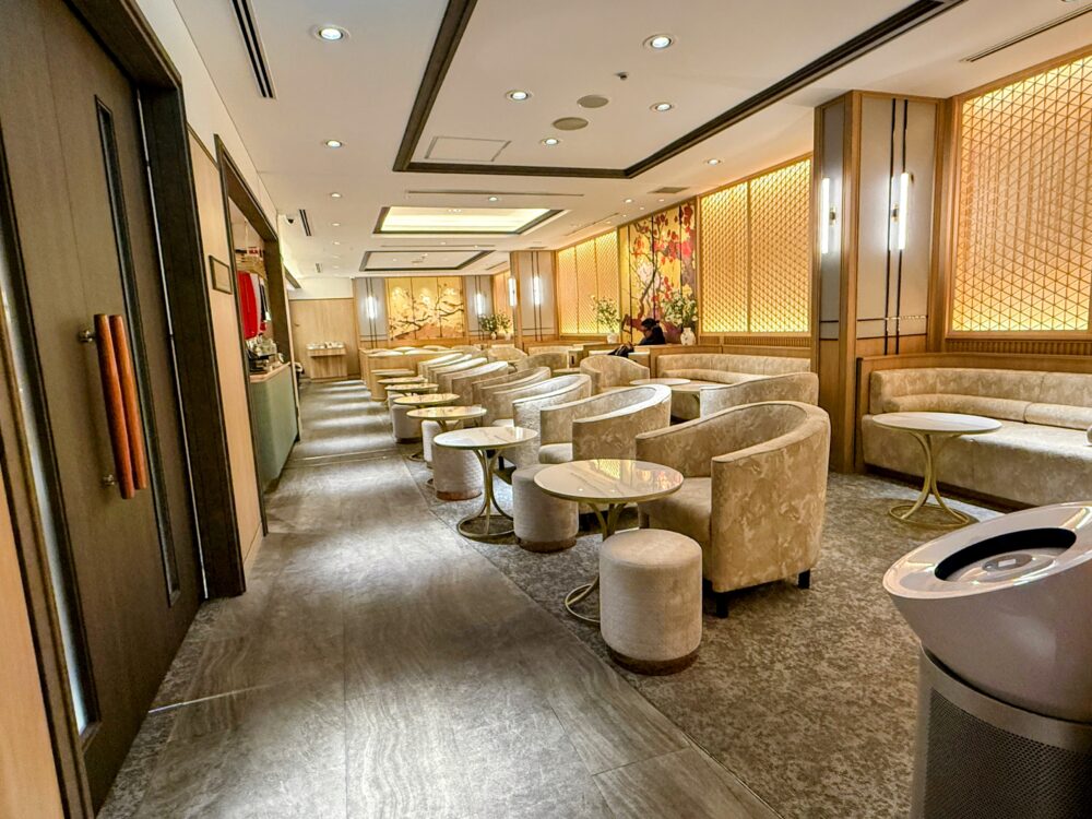 コーラルラウンジ楓のメイン席。壁面には日本の伝統的な格子模様と、鳥や花が描かれた金色の和風アートが飾られている。ゆったりとしたベージュのソファー席が並ぶ。