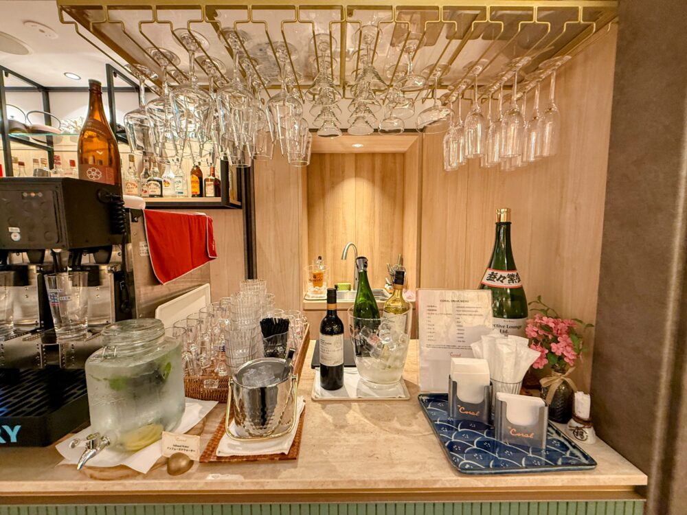 コーラルラウンジ楓（かえで）にあるバーカウンター。ワイングラスが吊り下げられ、カウンター奥には日本酒やワインボトルがディスプレイされている。