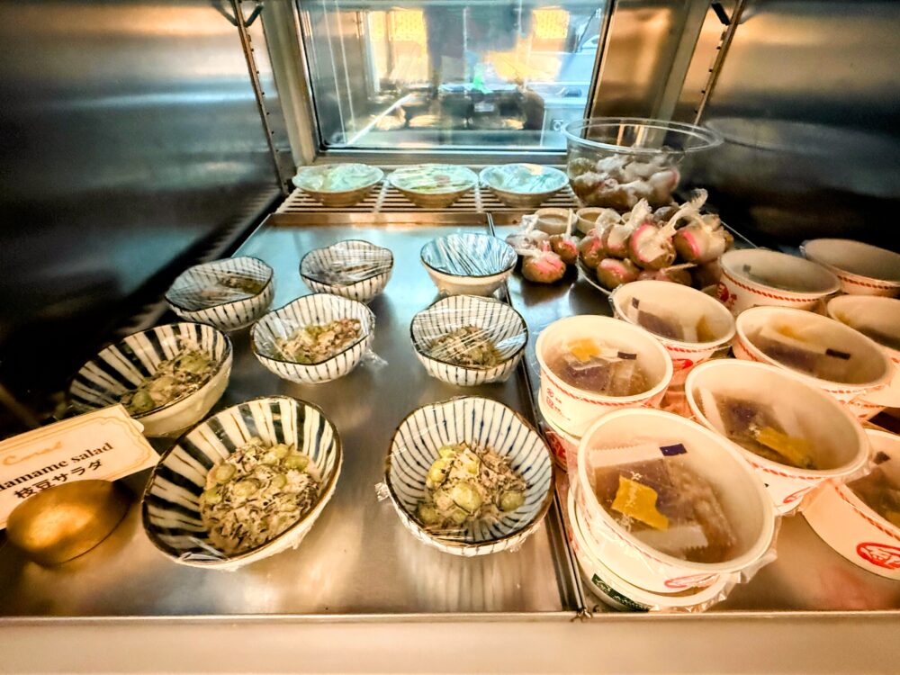 冷蔵ケースに並ぶ小鉢サラダ。枝豆を和えたヘルシーなサラダや、ひじき煮などの和惣菜が個別に盛り付けられている。