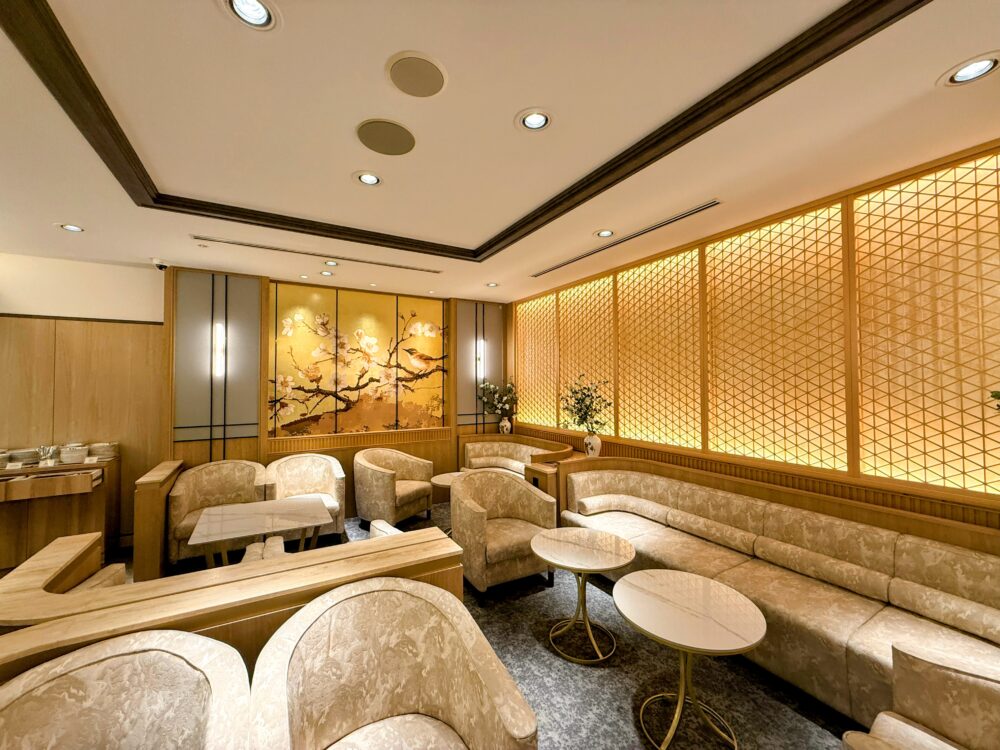 奥行きのあるラウンジ内の様子。間接照明に照らされた落ち着いた空間に、曲線的なデザインのソファーと大理石調の丸テーブルが配置されている。