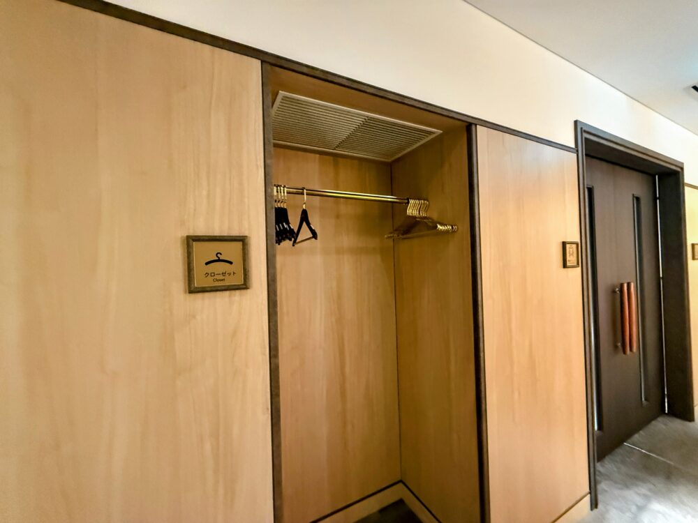 木目調の清潔なクローゼットスペース。ハンガーラックにハンガーが用意されており、コートや上着、手荷物を収納できる。