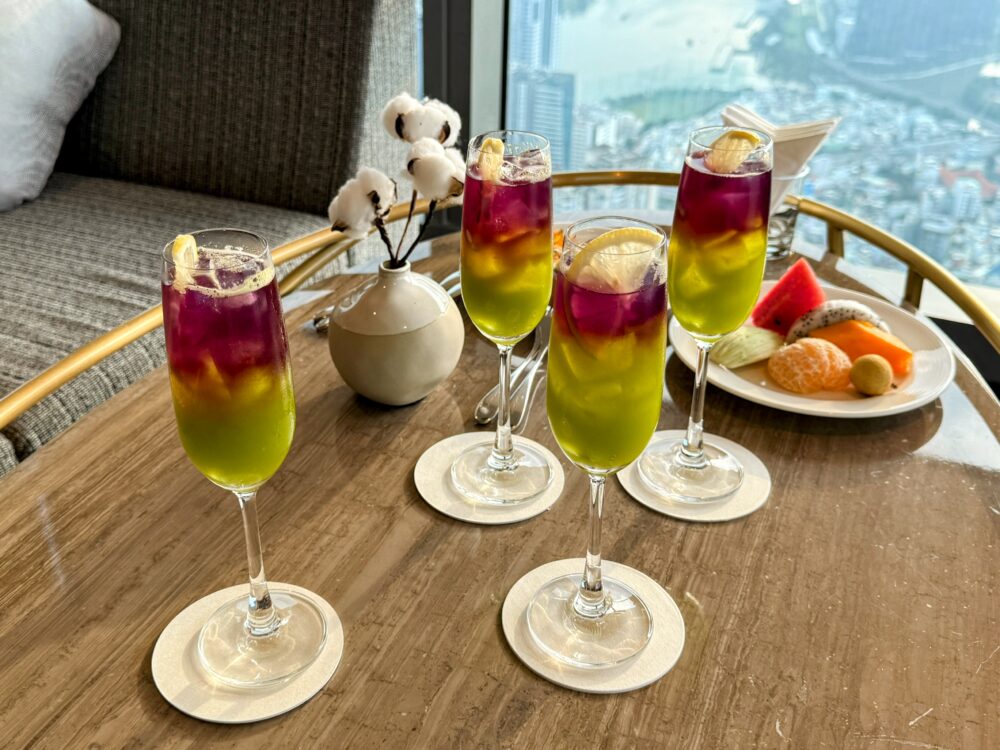 71階クラブラウンジ「Pearl Club」で提供された紫と黄色のグラデーションが美しいウェルカムドリンクと、窓から見えるホーチミンの景色。