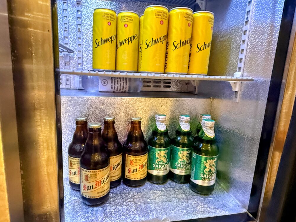 冷蔵庫に並ぶSchweppes(シュウェップス)のトニックウォーター缶と、San Miguel(サンミゲル)、Bia Saigon(ビア・サイゴン)の瓶ビール。