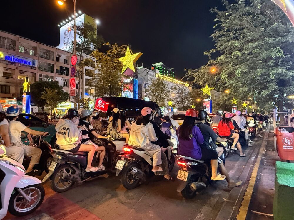 ホーチミンの夜の通りを行き交う多数のバイクと街のイルミネーション
