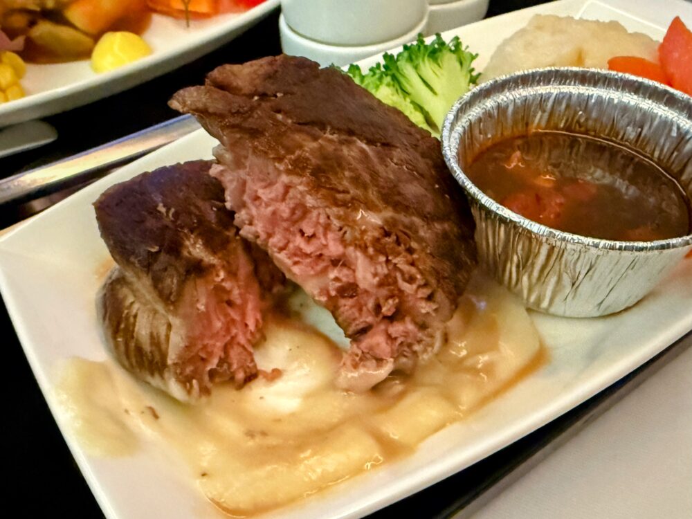 ミディアムレアの完璧な焼き加減で提供された牛フィレ肉のステーキ。断面は美しいピンク色で、濃厚なソースが添えられている。