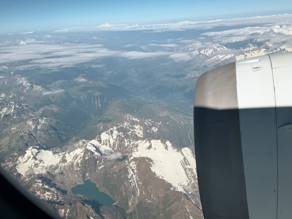 飛行機のエンジンの奥に広がる、雪を頂いた雄大なアルプス山脈の山並み。