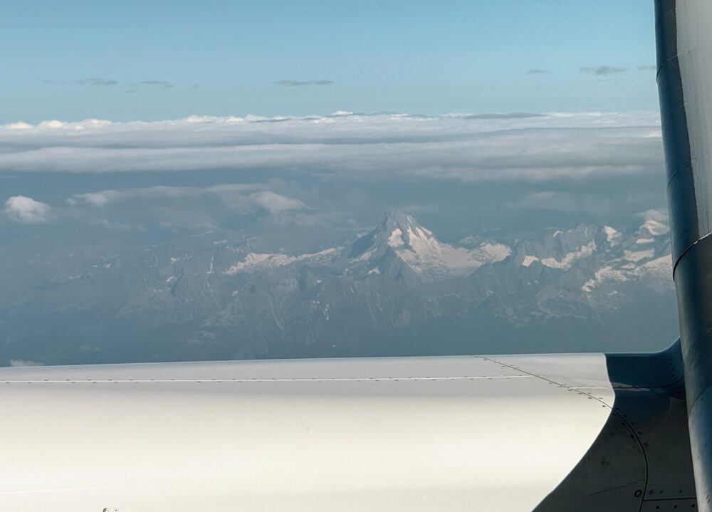 雲海の上に頭を出す、鋭く尖った雪山の頂。雲と山脈の幻想的な風景。