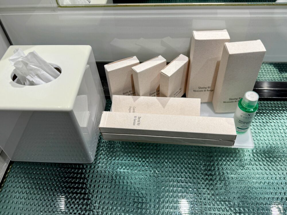 洗面台に置かれた箱入りのアメニティセット(シェービングキットなど)とティッシュボックス。