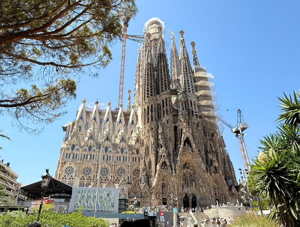 青空にそびえ立つサグラダ・ファミリアの全体像。塔の彫刻が美しい。