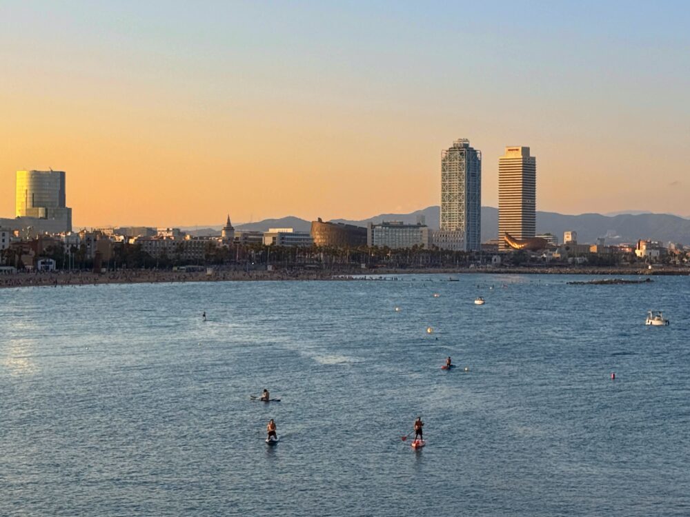 夕日に染まるバルセロナの海と遠くに見えるバルセロナのビル。