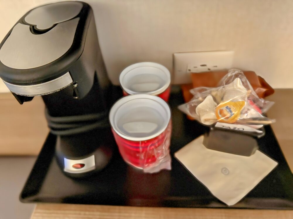 客室に備え付けのコーヒーメーカーと、テイクアウト用カップ、コーヒー・紅茶のセット。