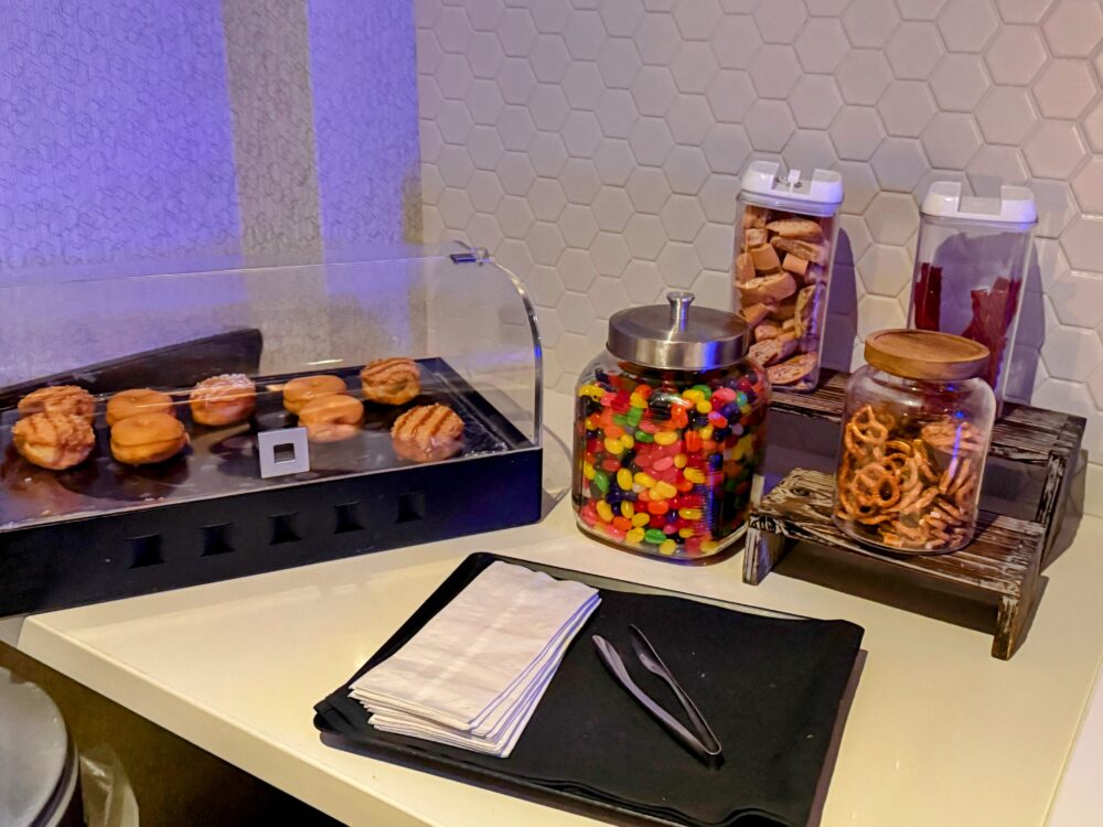 ラウンジに用意された軽食コーナー。ドーナッツ、プレッツェル、ジェリービーンズなどのスナックが瓶に入って並べられている。