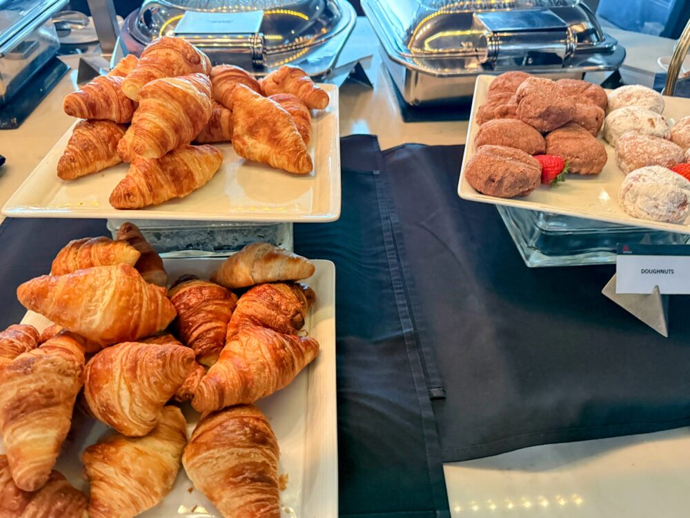 ビュッフェ台に並ぶ焼きたてのクロワッサン、デニッシュ、ドーナツなどのパン類。