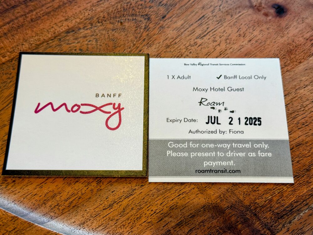 木のテーブルに置かれた、「Moxy Hotel Guest Roam」とスタンプされた宿泊者専用の無料バスチケット。