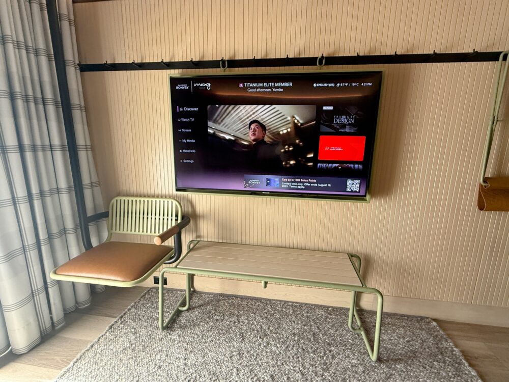 壁掛け収納(ペグウォール)に掛けられた椅子とテーブル、壁掛けテレビ。