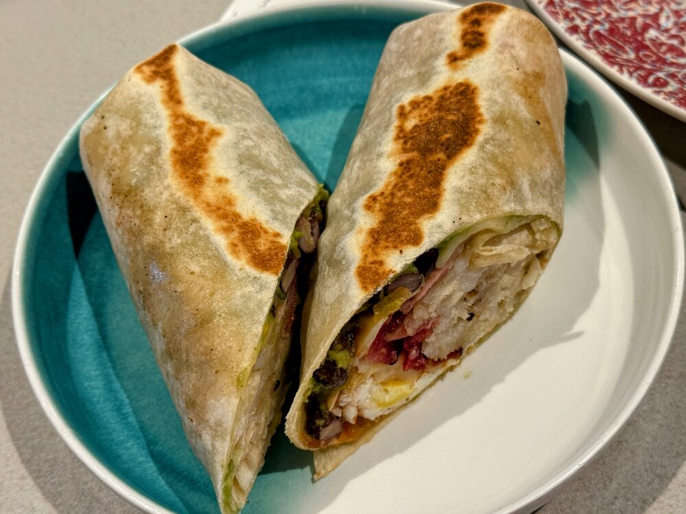 具材がぎっしり詰まった朝食ブリトーの断面。鮮やかな青い皿に盛り付けられている。