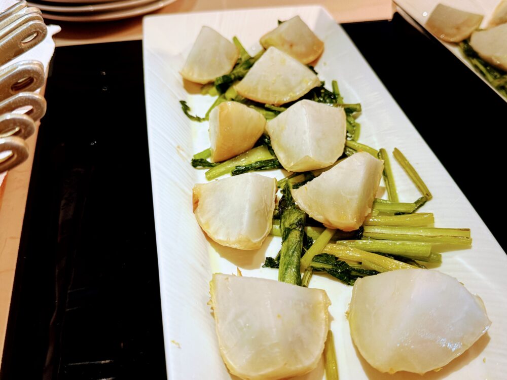 白い長皿に盛り付けられたカブのロースト。半月形にカットされた白いカブと菜の花が交互に並び、シンプルながら上品な仕上がりの一皿。