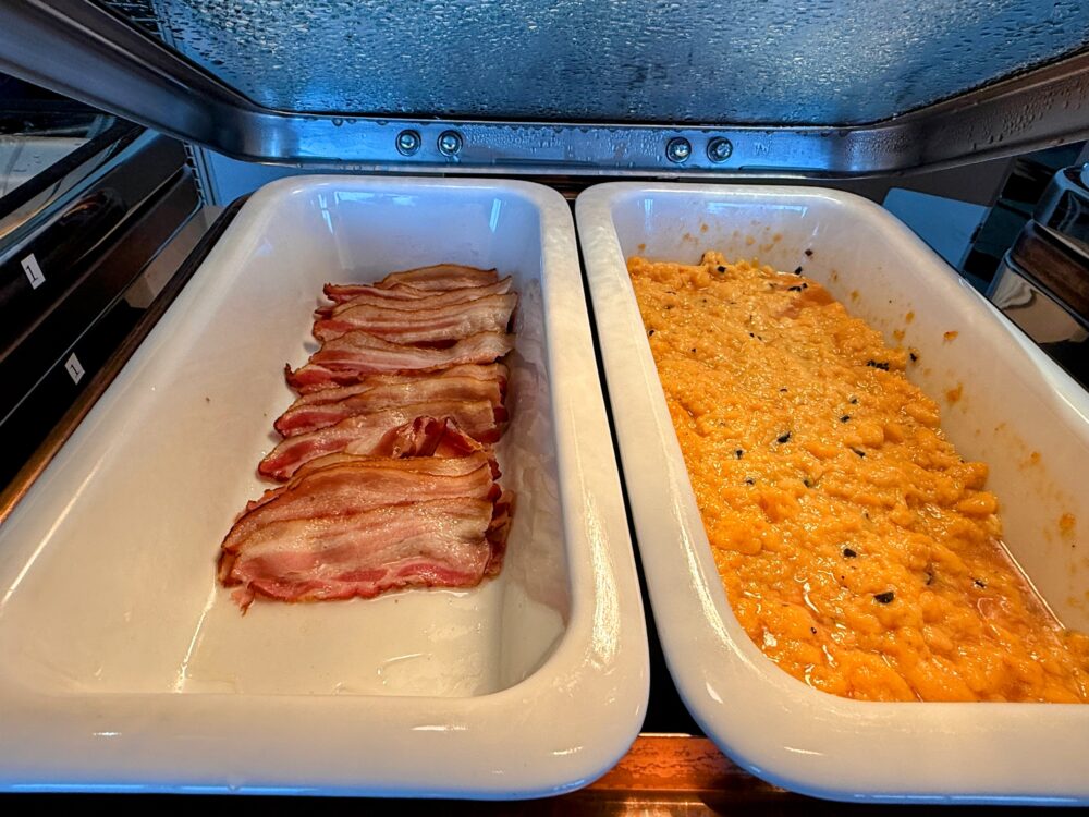 大阪ステーションホテル スペシャリティサロンの朝食ビュッフェのホットミールコーナー。カリカリのベーコンと鮮やかなオレンジ色のスクランブルエッグが並ぶ。
