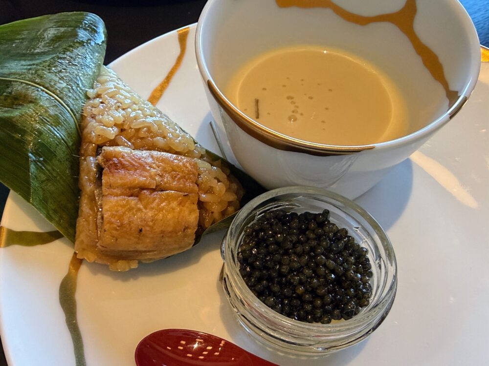 大阪ステーションホテル スペシャリティサロンのコース料理。竹の葉に包まれた中華ちまきと黒豆のポタージュ、キャビアが1皿にセットで提供されている。
