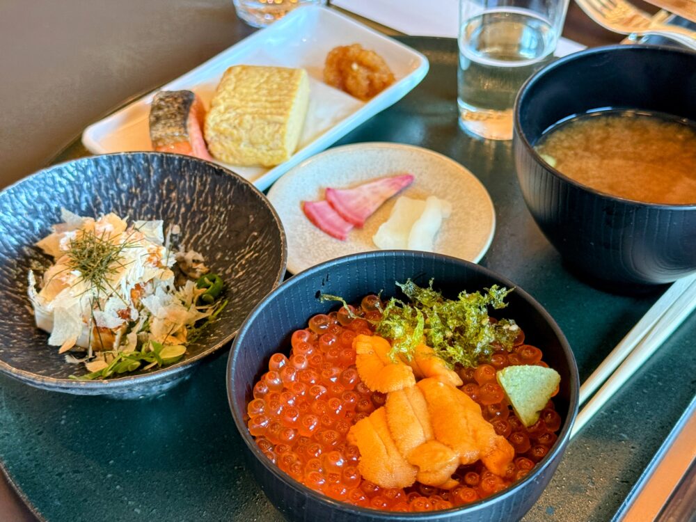 スペシャリティサロンの和朝食セット。手前に雲丹といくらの丼ぶりとしじみ汁、奥の白い長皿に出汁巻き・季節の焼き魚・漬物が盛り付けられ、最初からセットで提供されている。