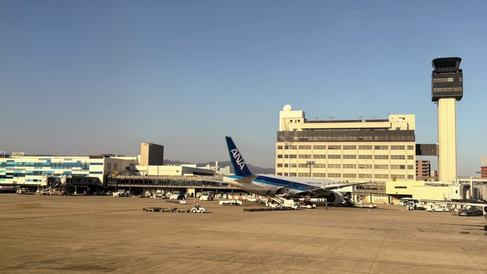 伊丹空港を出発するANA機の機窓から見えた空港の風景と駐機中の飛行機。