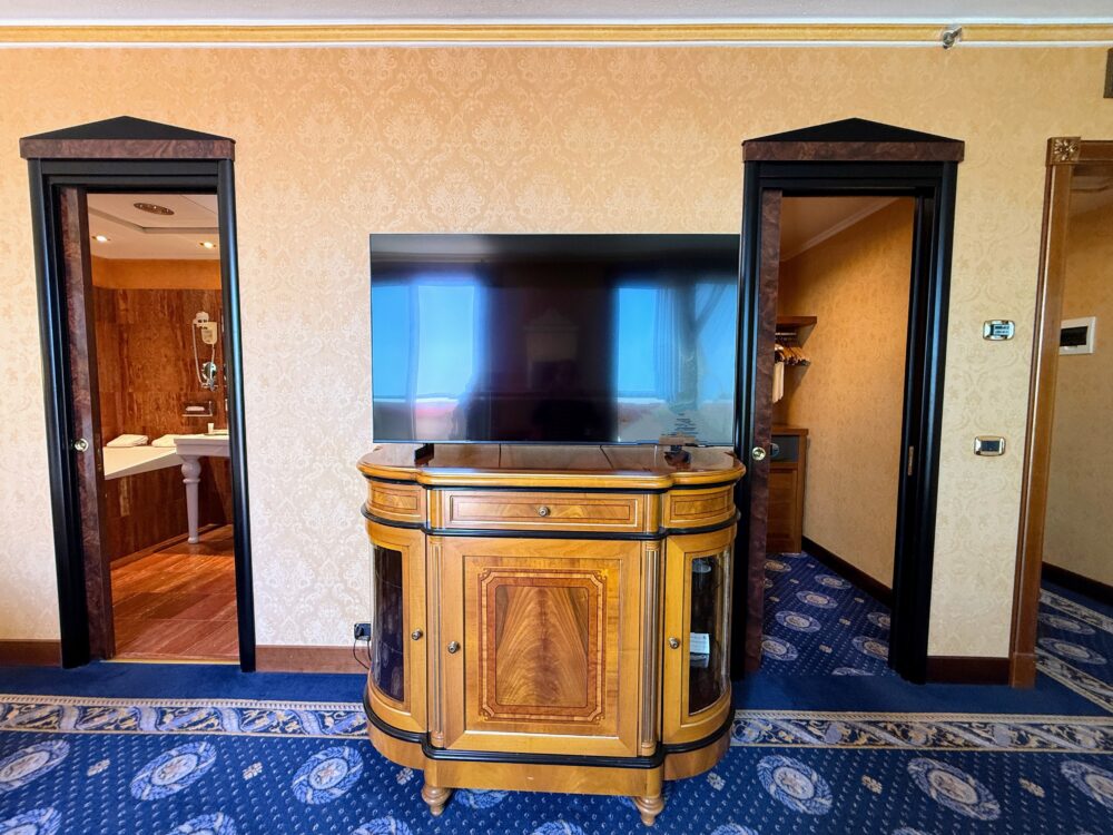 クラシックな木製のテレビボードと液晶テレビ。その左右にはバスルームとクローゼットに通じる2つの入り口があり、回遊できる間取りになっている。