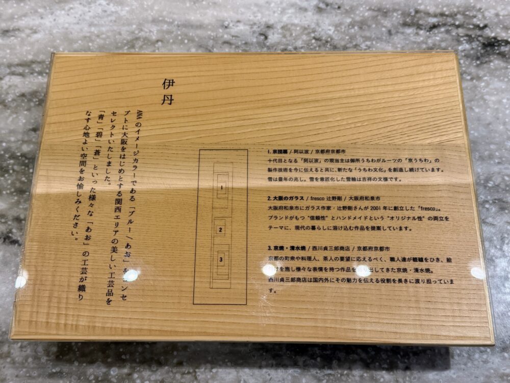 伊丹空港ANAスイートラウンジに展示された工芸品の解説パネル。ANAのイメージカラー「ブルー」をテーマに、京団扇・大阪のガラス・京焼の3点が紹介されている。