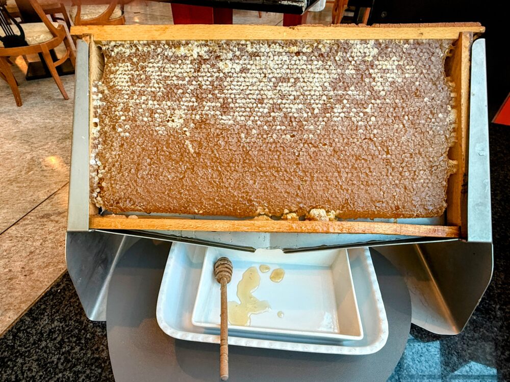 木枠に入った大きな天然の巣蜜(コムハニー)と、そこから滴るハチミツ。