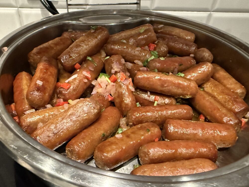 朝食用のポークソーセージ。焼き色がついており、玉ねぎやパプリカと一緒に調理されている。