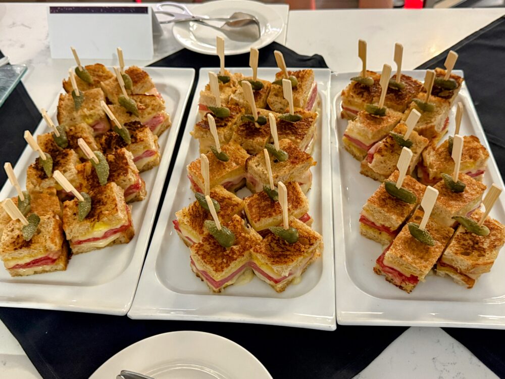 こんがりと焼かれたホットサンドイッチ(パニーニ風)。串に刺されており、手軽につまめるフィンガーフード。