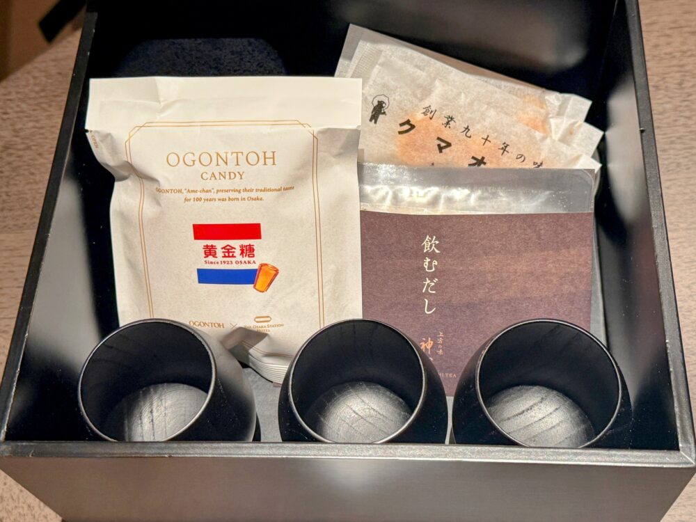 客室に用意されたお茶菓子セット。大阪名物の「黄金糖(キャンディ)」、「飲むだし」、おかきなどが黒い箱に入っている。