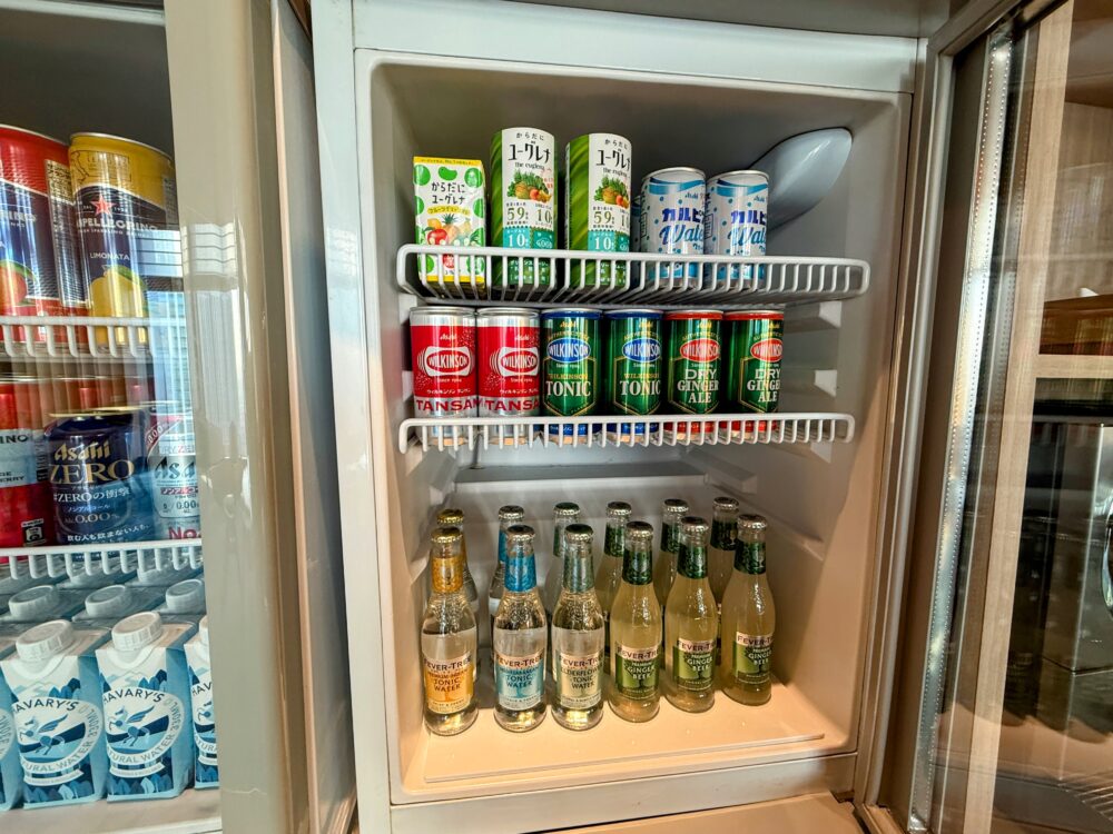 ショーケース冷蔵庫。ユーグレナ飲料、カルピスウォーター、ウィルキンソンの炭酸水各種、フィーバーツリーのトニックウォーターやジンジャービアの瓶が並ぶ。