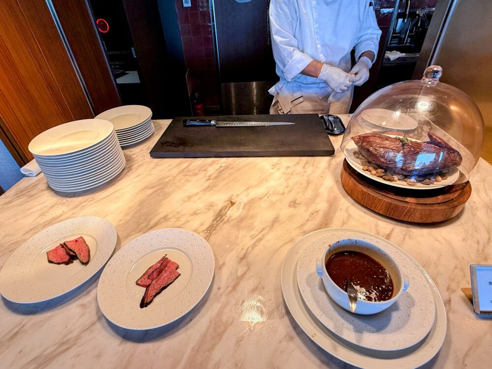 ライブキッチンでシェフが大きなローストビーフを切り分けている様子。手前にはスライスされたお肉と特製ソースが用意されている。